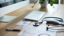 A table with a computer, a stethoscope and information about early retirement health care options