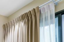 Professional tailor adjusting and hemming elegant curtains in a modern Dubai home