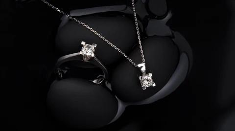solitaire diamond ring and a diamond pendant with chain is displaying against a black background.